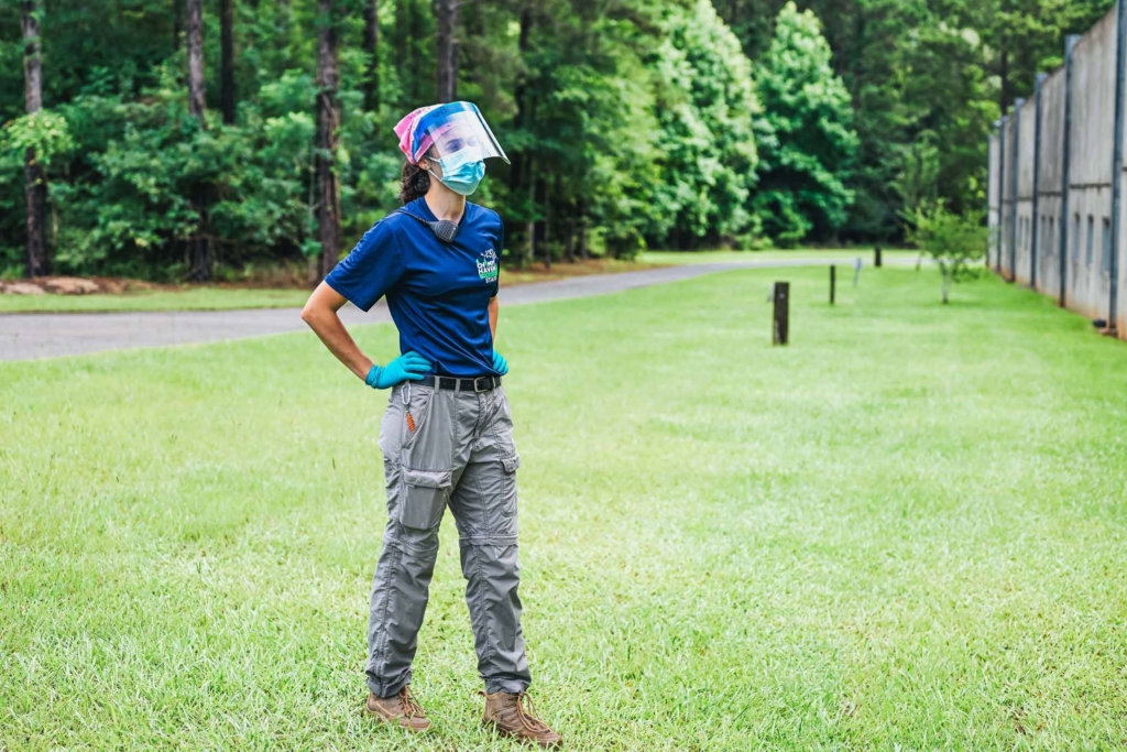 Chimp Haven Caregiver Stands in Uniform Outside of Chimpanzee Play Yard